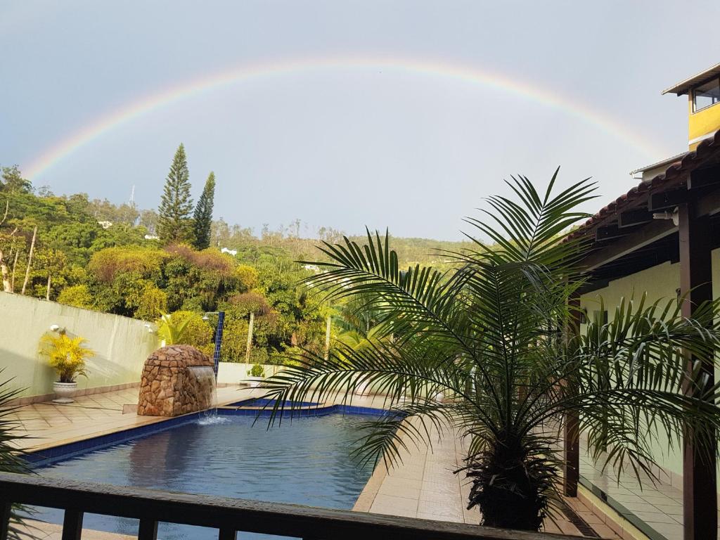 a rainbow over a swimming pool with a palm tree at Pousada Queiroz in Barra da Tijuca