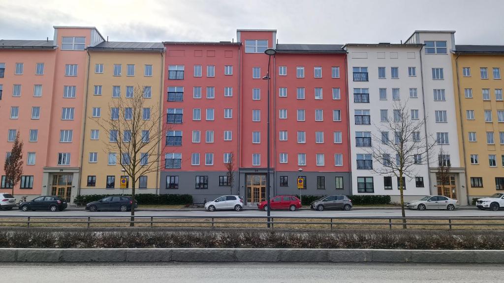 una fila di edifici con auto parcheggiate in un parcheggio di Cozy-Mozy a Stoccolma