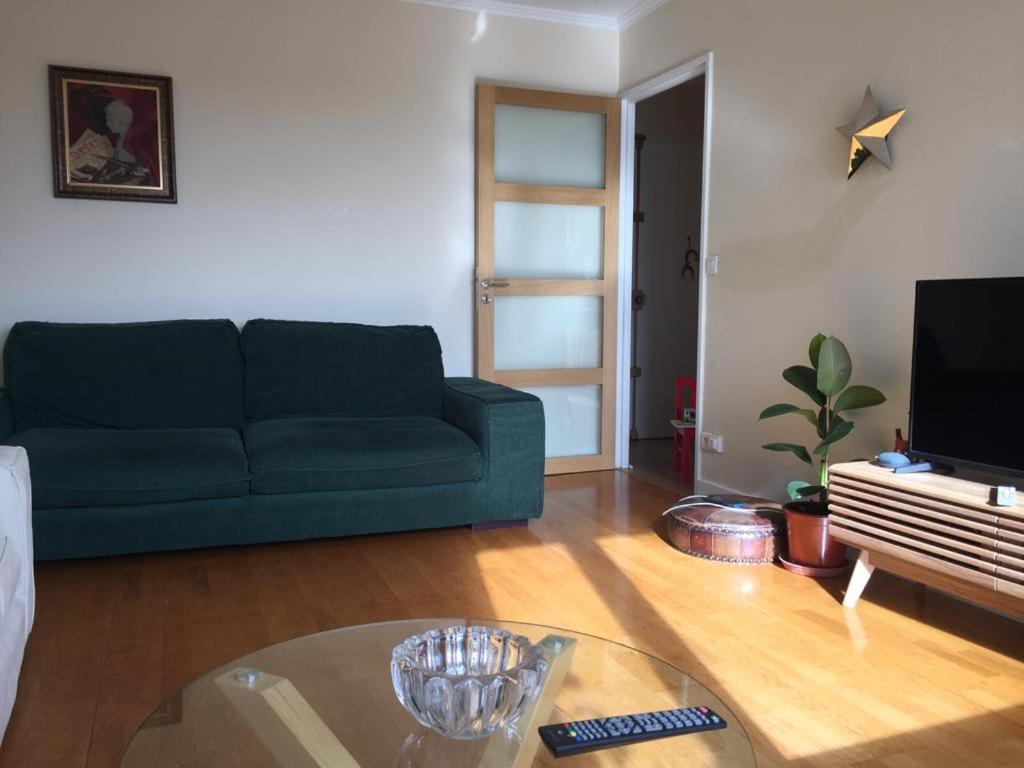 uma sala de estar com um sofá verde e uma mesa em Appartement Taverny em Taverny