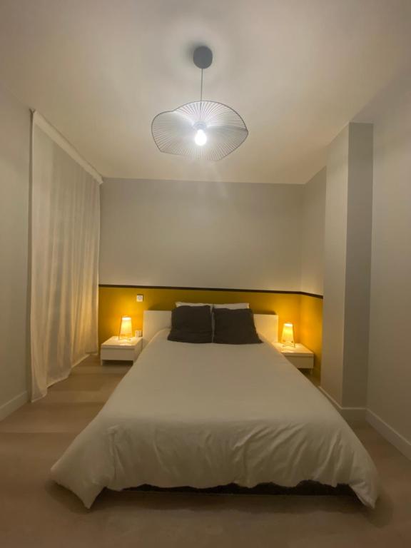 a bedroom with a large white bed with two lamps at 45m² rez-de-chaussée au calme centre-ville in Mayenne