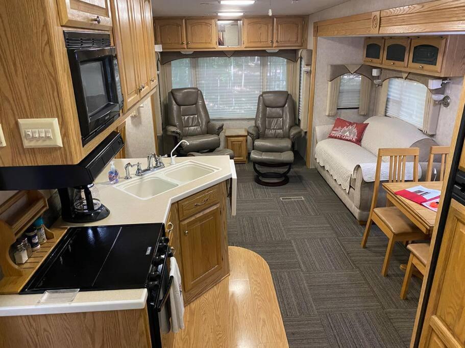 a kitchen with a sink and a bedroom with a bed at Betsie -35Ft RV Camper in Woods -Firepit & Hot Tub in Benzonia