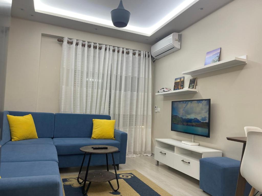 een woonkamer met een blauwe bank en een tv bij Sirel Home in Durrës