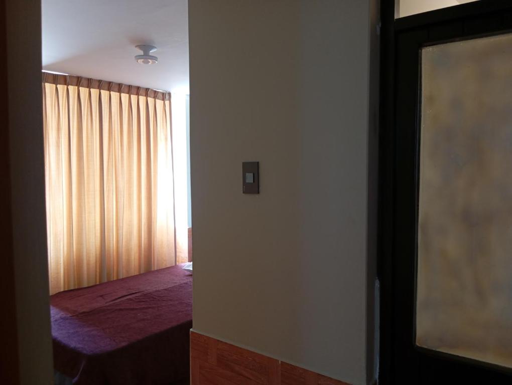 um quarto com uma cama e uma janela com uma cortina em Goya'sHostel em Camaná
