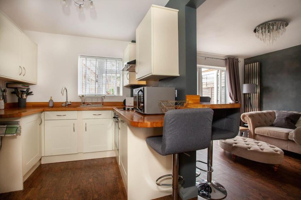 cocina con armarios blancos y encimera en Three Bedroom House, Driveway, Bracknell Centre en Bracknell