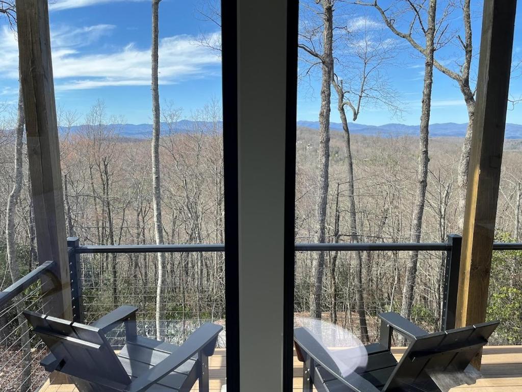 a view from the porch of a house with two chairs at The Brevard Mountain Retreat New Construction with modern design, high-end furnishings & hot tub in Cedar Mountain