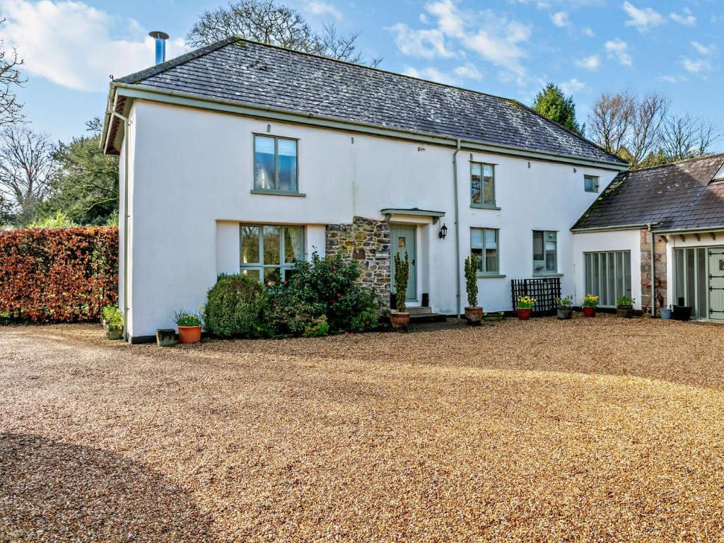 a white house with a gravel driveway at 4 bed in Okehampton 49511 in Sampford Courtenay