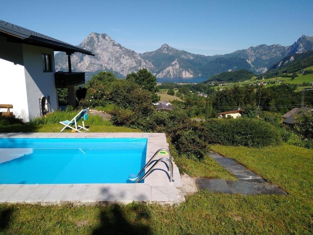 a swimming pool with a chair next to a house at Gemütliches Landhaus in Panorama-Lage mit herrlichem See- und Bergblick in Vichtau