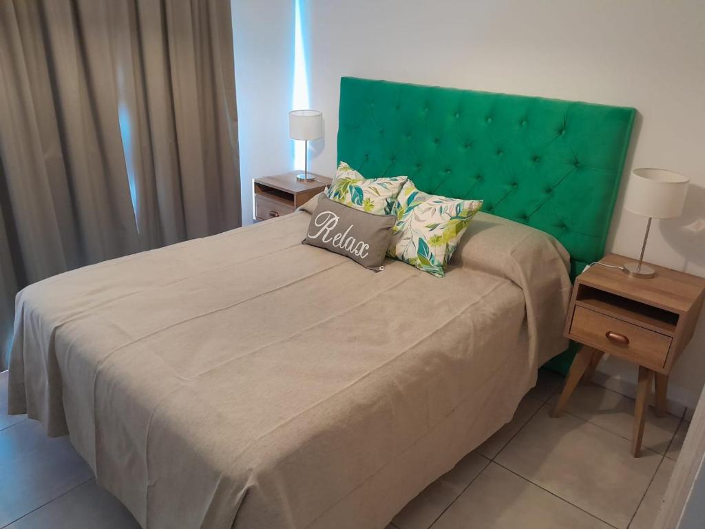 een slaapkamer met een groot bed met een groen hoofdeinde bij URBANO Dpto in Villa María