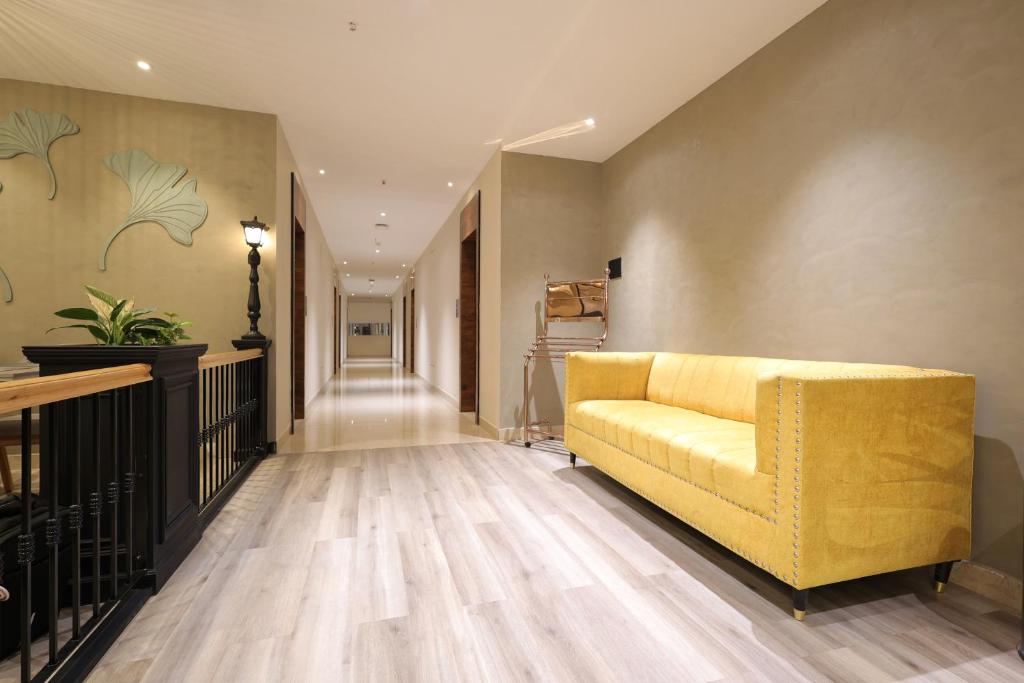 un soggiorno con divano giallo e un corridoio di Hotel Aurum Keys - ORR Bagmane Tech Park a Bangalore