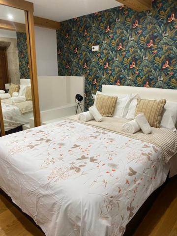 a bedroom with a white bed with a floral wallpaper at Apartamento con vistas a la catedral in Santiago de Compostela