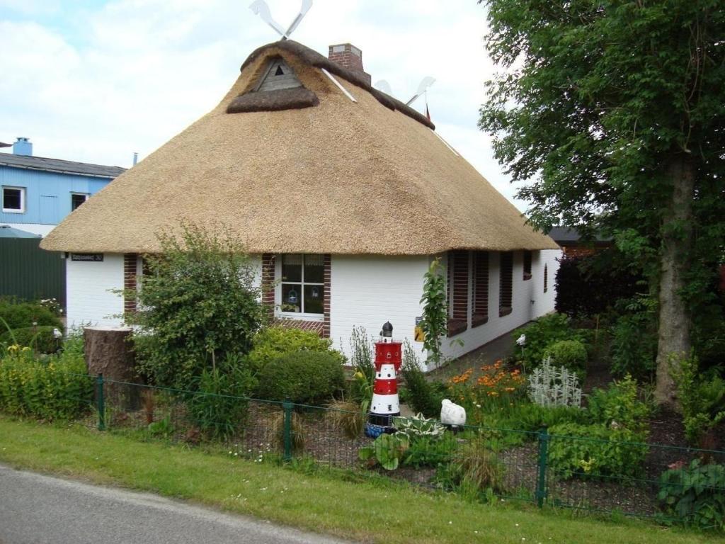 een klein wit huis met een rieten dak bij Ferienhaus in Rathjensdorf mit Grill, Garten und Terrasse in Kronprinzenkoog