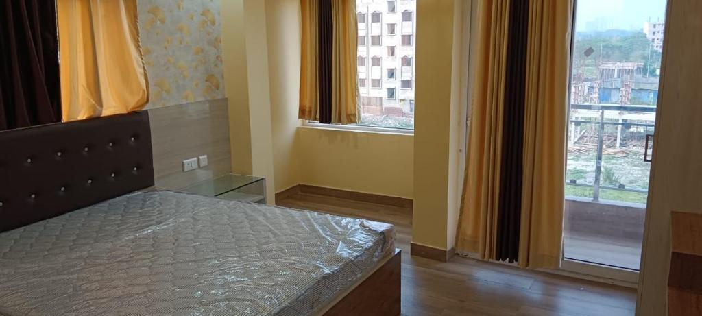 sypialnia z łóżkiem i dwoma dużymi oknami w obiekcie Hotel Reliance w mieście kolkata