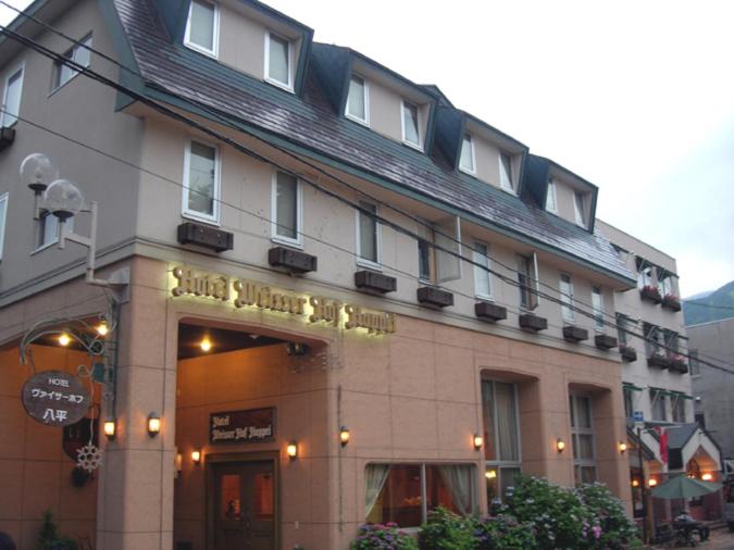 a building with a sign on the front of it at Hotel Weisser Hof Happei in Hakuba