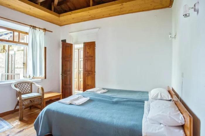 una camera con un letto e una sedia e una finestra di Sotos pension a Skopelos Town