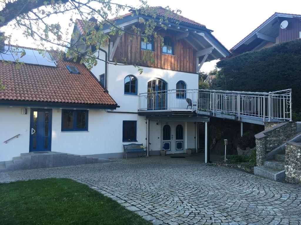 a white house with a balcony and a patio at Ferienwohnung für 2 Personen im Bayerischen Wald in Neureichenau