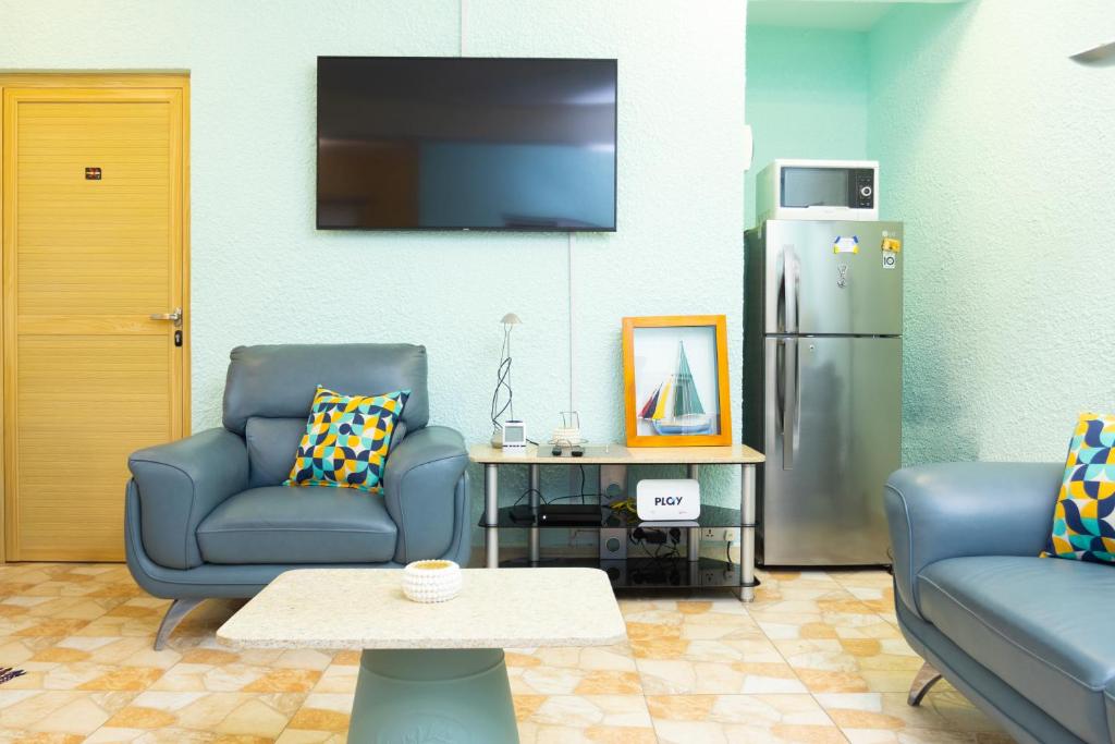 a living room with two chairs and a refrigerator at Appartement neuf au cœur de Quatre Bornes in Quatre Bornes