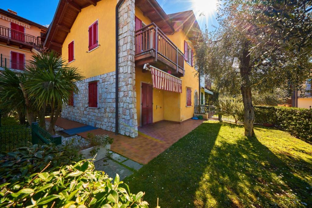 un grand bâtiment jaune avec des fenêtres rouges et une cour dans l'établissement A Casa di Anna Maria, à Brenzone