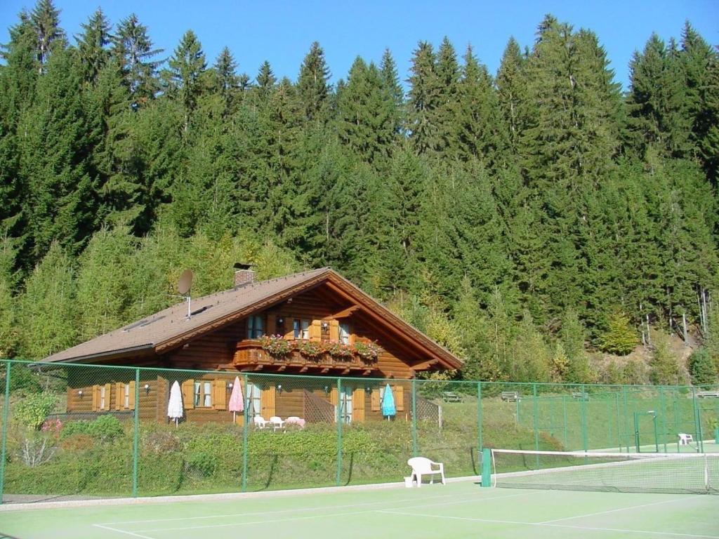 a house on a tennis court next to a tennis court at Holzblockhaus auf zwei Etagen mit Whirlbadewanne und Kaminofen in Berg im Drautal