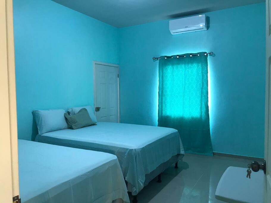 ein blaues Zimmer mit 2 Betten und einem Fenster in der Unterkunft Tu mejor opción in Juticalpa
