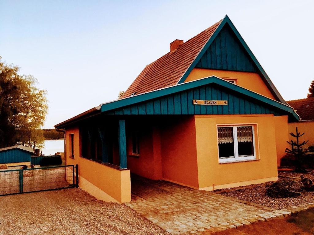 una pequeña casa con techo azul y valla en Feriengrundstück direkt am See, en Dabel