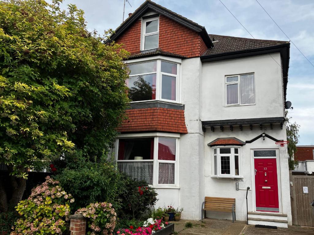 une maison blanche avec une porte rouge dans l'établissement Sylvian, à Bexhill-on-Sea