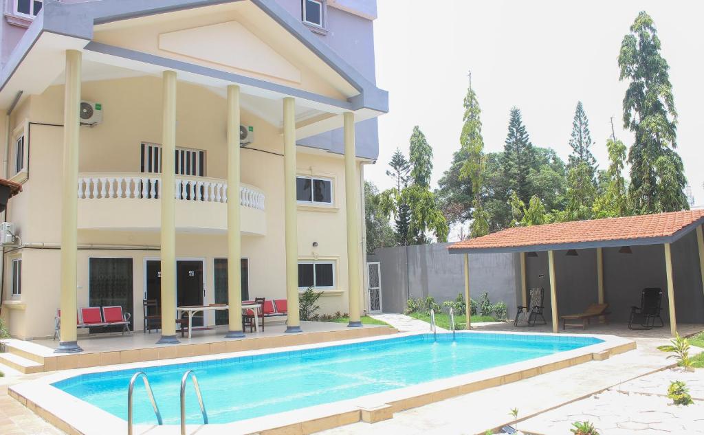 a villa with a swimming pool in front of a house at Hotel BKBG Benin in Cotonou