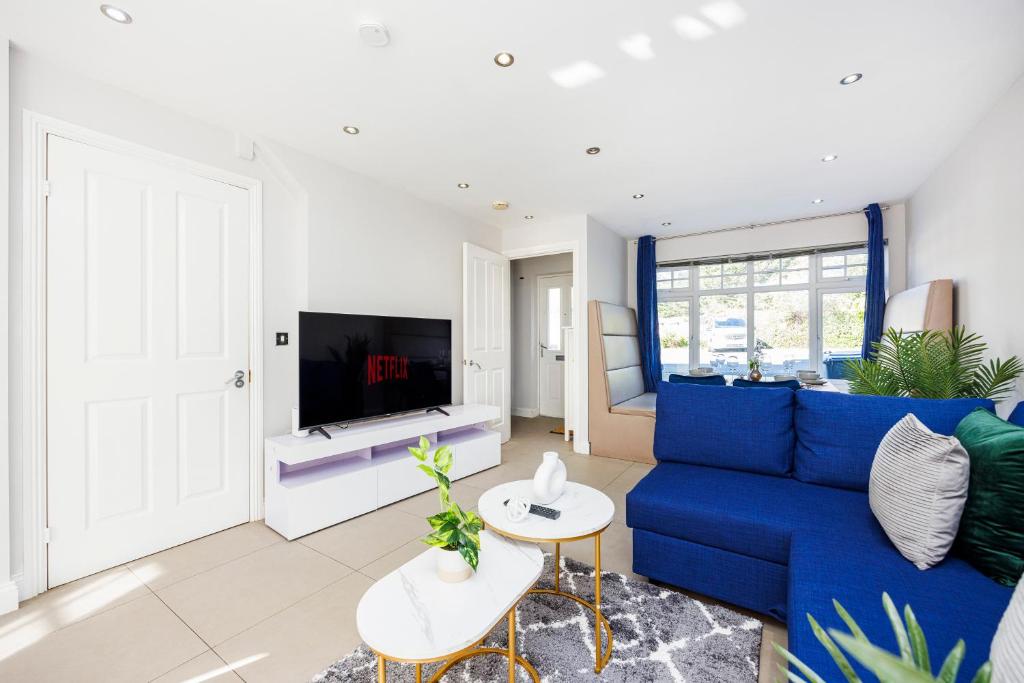 4 Bed Townhouse in Uxbridge Ideal For Families or Contractors في هيلينغدون: غرفة معيشة مع أريكة زرقاء وتلفزيون