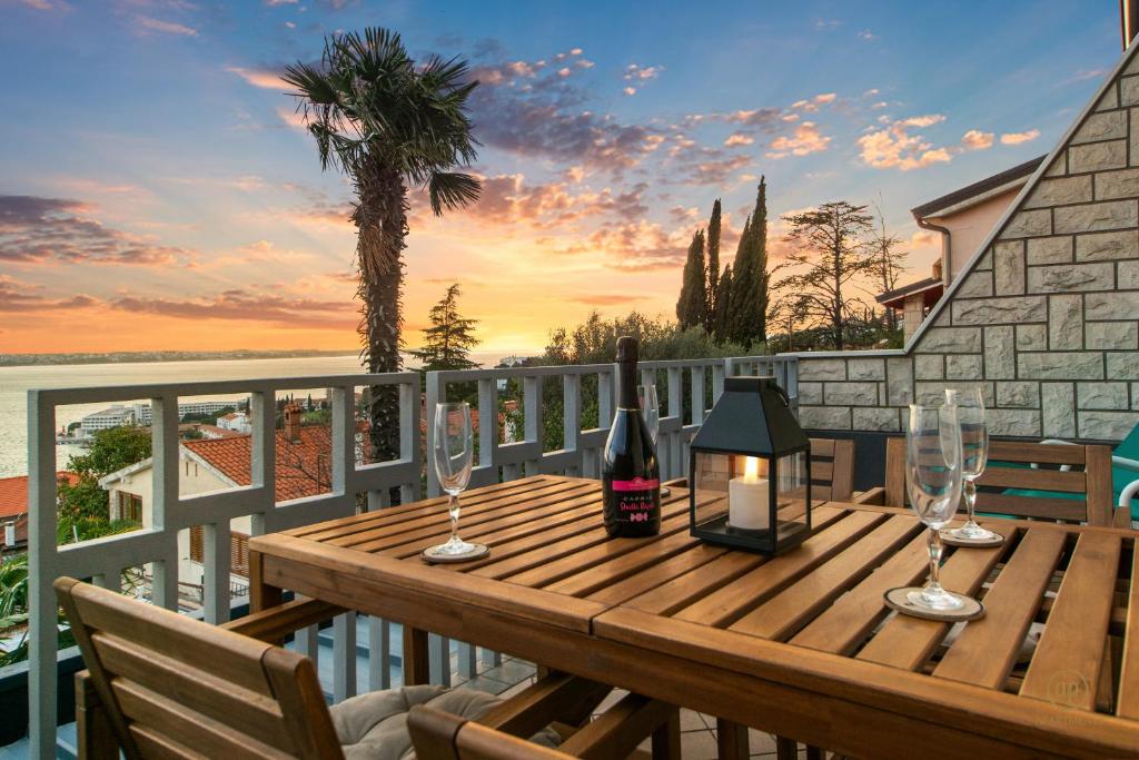un tavolo in legno con bicchieri da vino e una candela sul balcone di ARIA Superior Apartment, Seaview & Wellness a Portoroz
