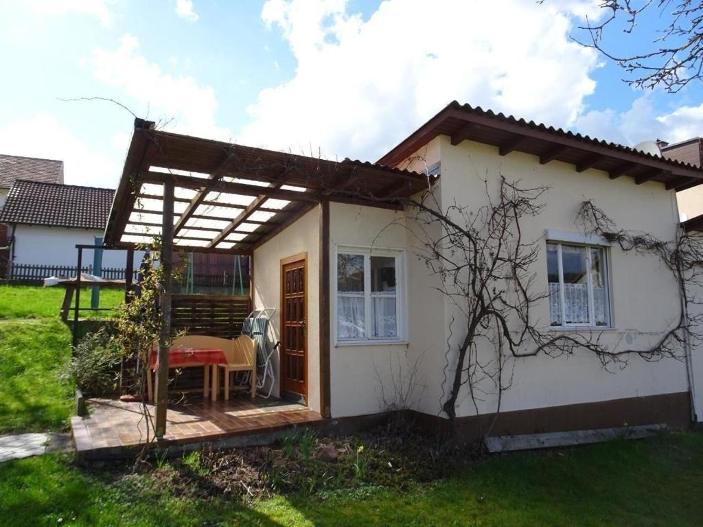 una pequeña casa blanca con pérgola en Kleines Ferienhaus in Garitz mit Garten, Terrasse und Grill, en Bad Kissingen