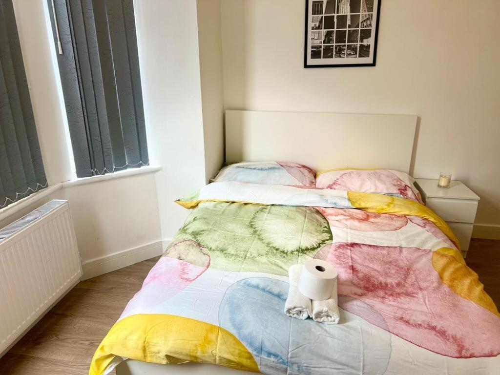 En-suit double bedroom with bathroom in Manchester في مانشستر: غرفة نوم مع سرير وبطانية ملونة