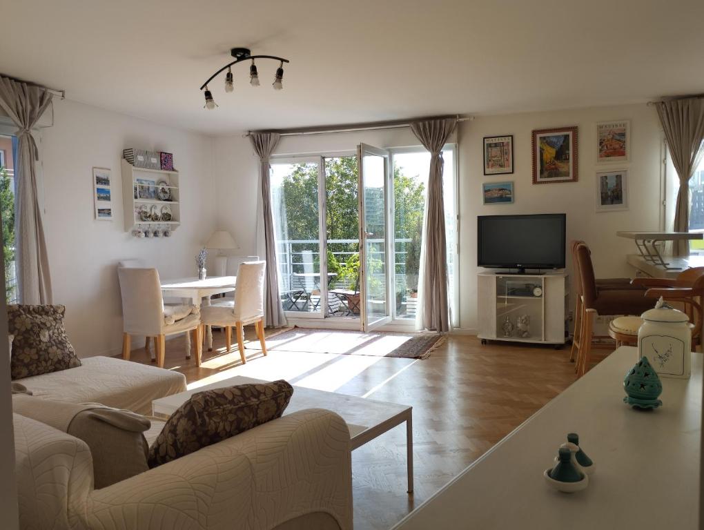 un salon avec un canapé, une télévision et une table dans l'établissement Appartement proche Village Olympique au pied du métro Carrefour Pleyel, à Saint-Denis