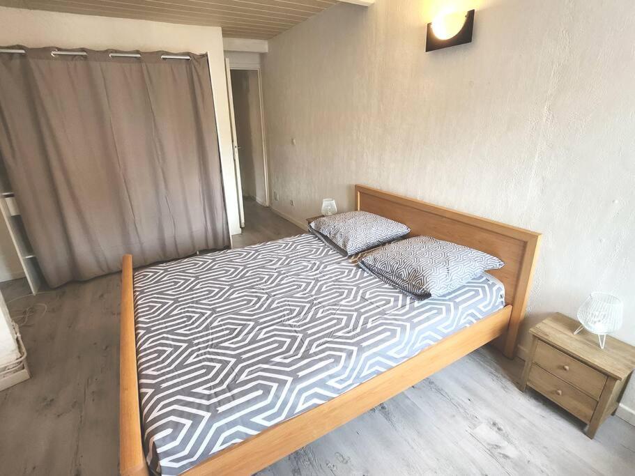 - une chambre avec un lit doté d'un cadre en bois dans l'établissement Maison à 9 minutes de la plage, à Bompas