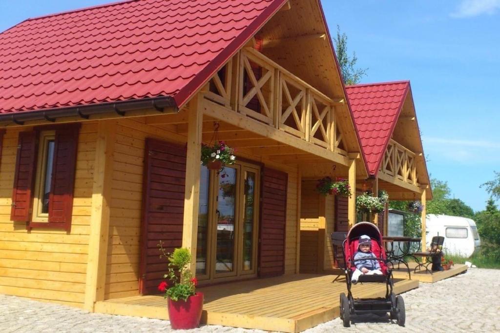 a small wooden house with a stroller in front of it at Villa Amber - b43068 in Gąski