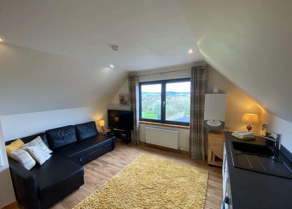 a living room with a black couch and a window at Brohar Annexe in Inverness