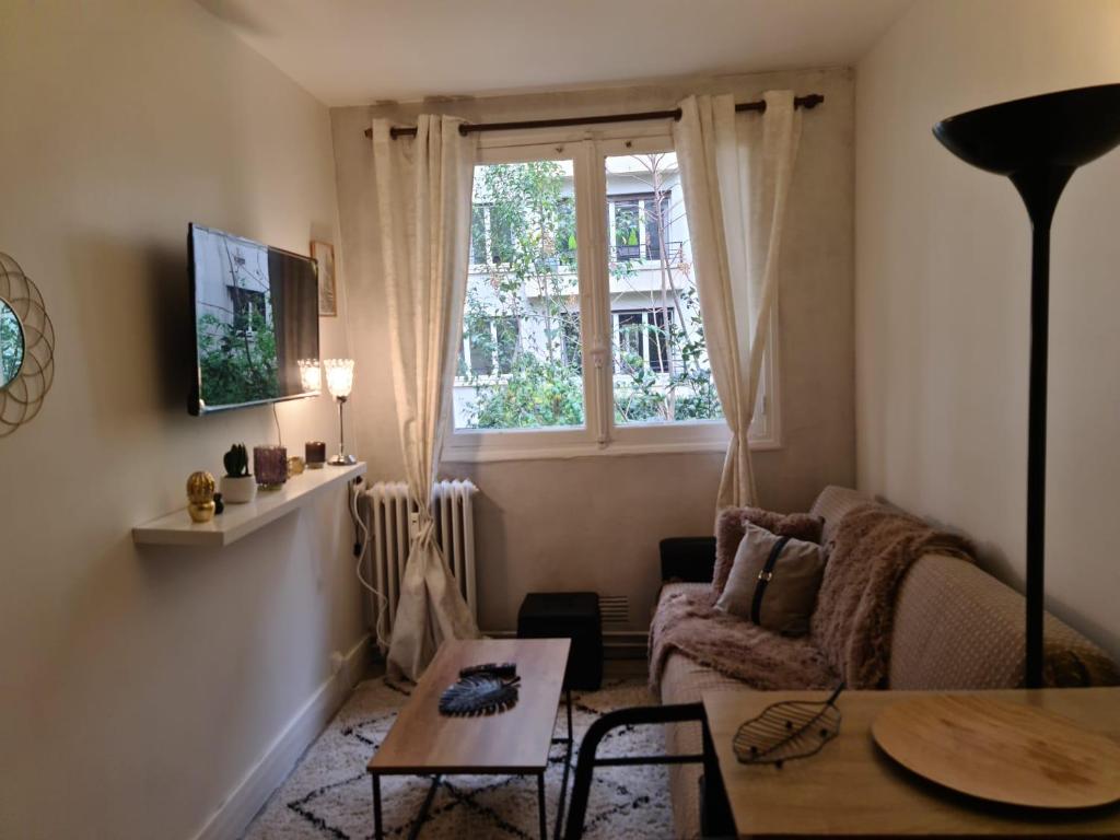 Appartement Jasmin 16ème في باريس: غرفة معيشة مع أريكة وطاولة ونافذة