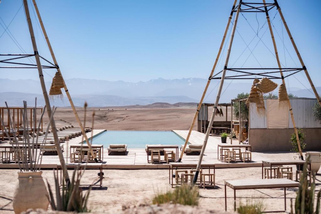 eine Gruppe Stühle und ein Pool in der Wüste in der Unterkunft Les Terrasses d'Agafay in El Karia
