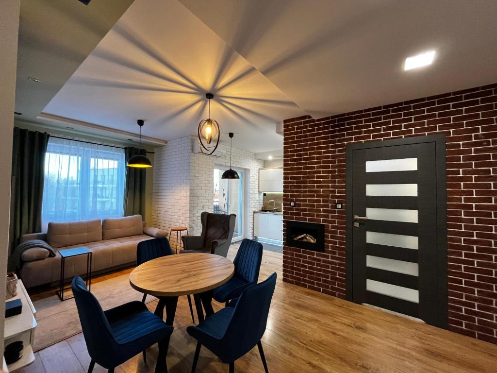 a living room with a table and chairs and a brick wall at Apartament Ezuka - Twoje miejsce na mazurach in Giżycko