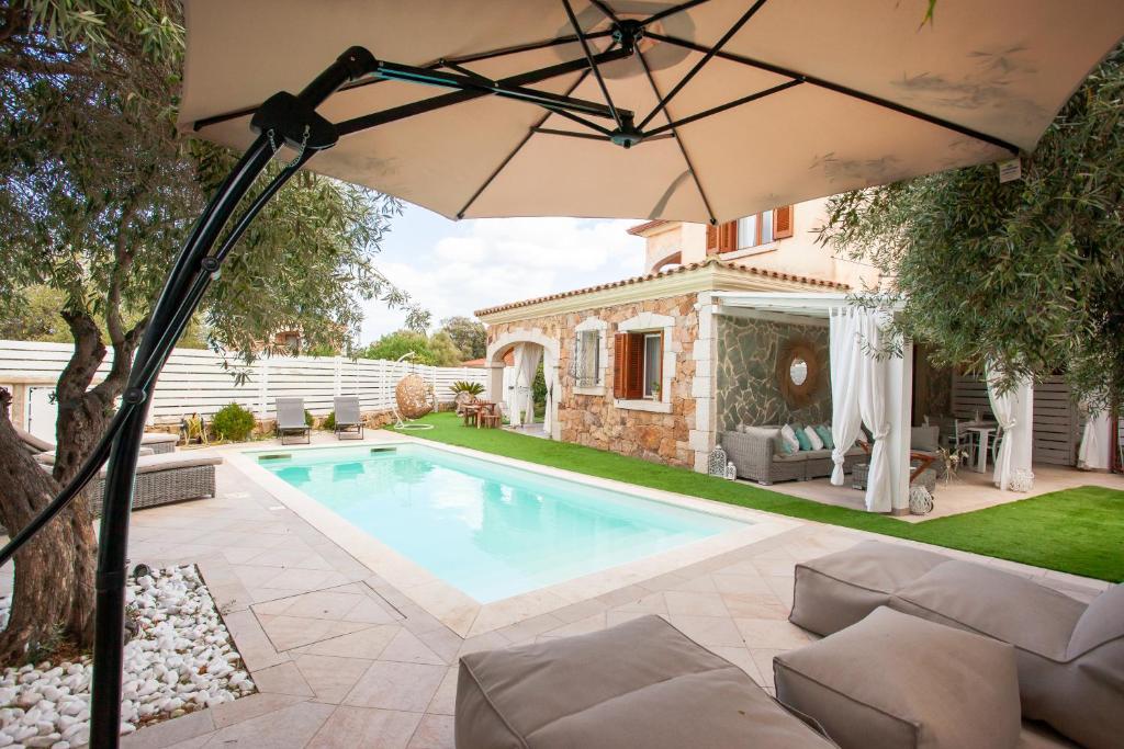 a house with a swimming pool and an umbrella at Villa Coclea con piscina in San Teodoro