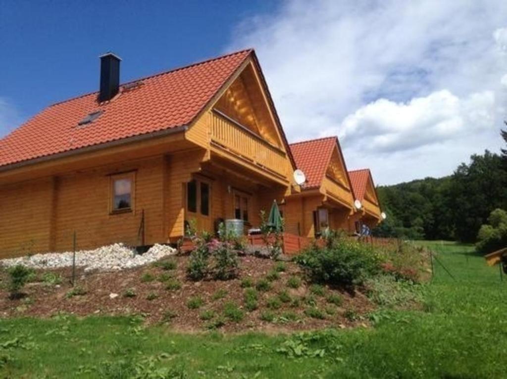 ein Holzhaus mit rotem Dach in der Unterkunft Harzer Blockhaus III in Bad Sachsa