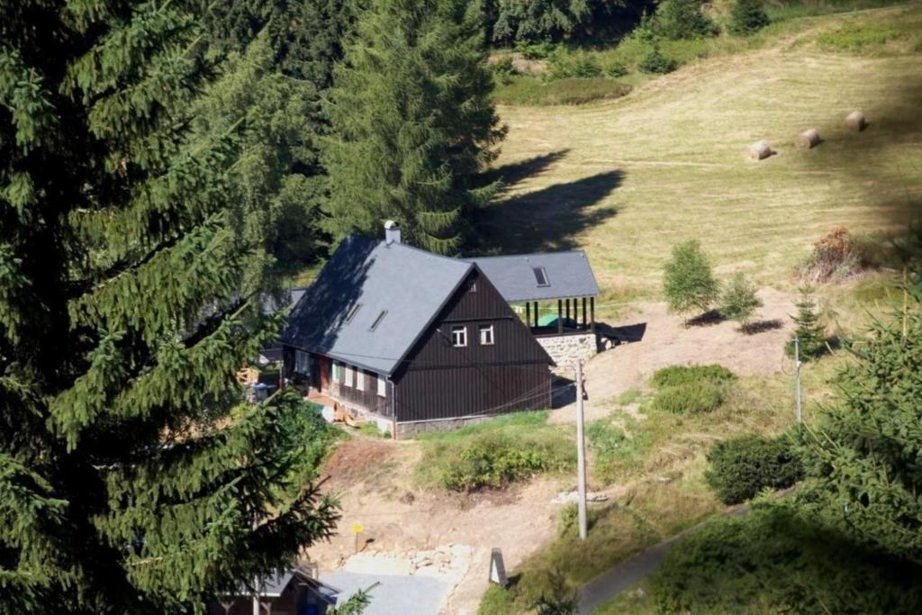 une vue aérienne d'une grange noire dans un champ dans l'établissement Appartement in Klingenthal mit Terrasse, Garten und Grill, à Klingenthal