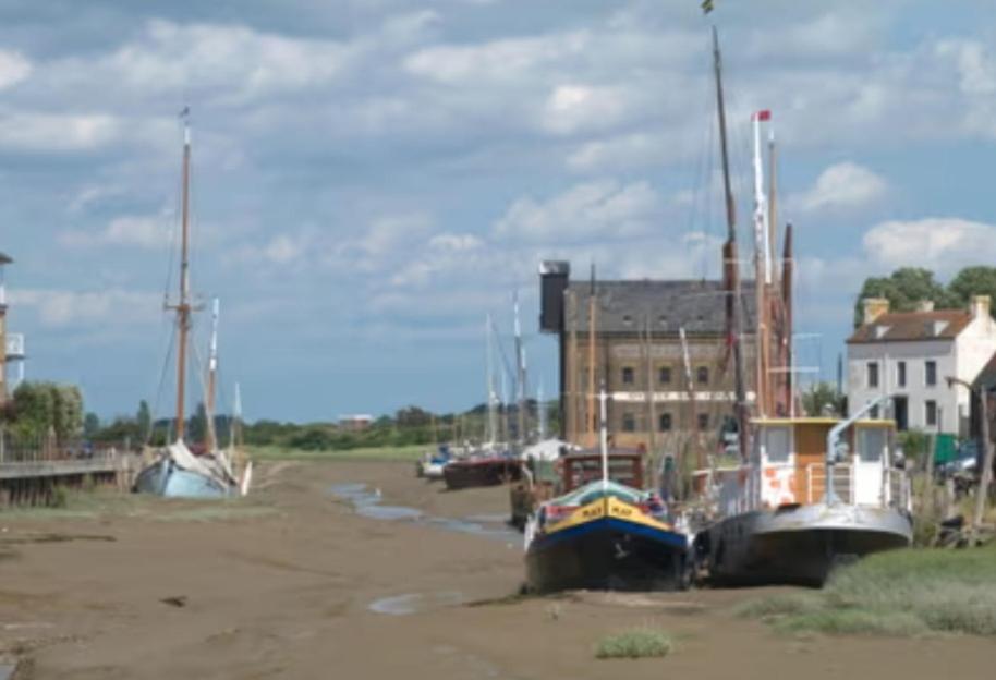 a group of boats sitting in the sand next to a building at The oast @ faversham in Kent