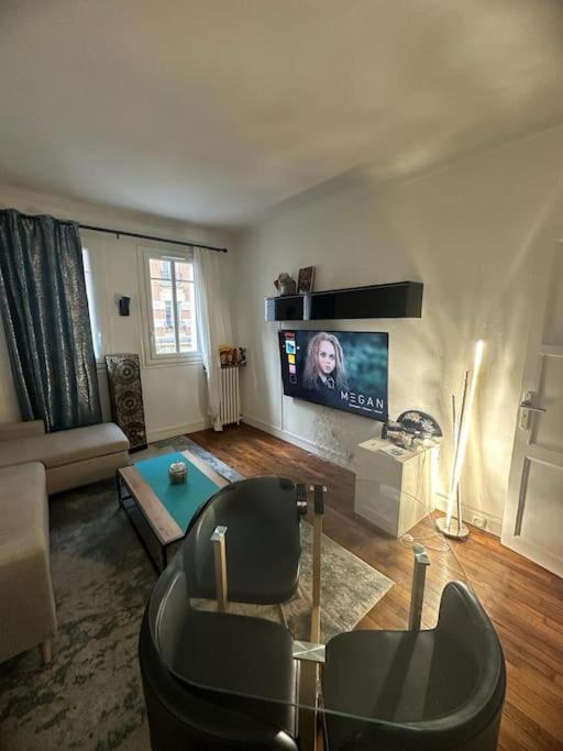 een woonkamer met een bank en een tv bij Appartement de charme- Proche JO Paris 24 in Colombes