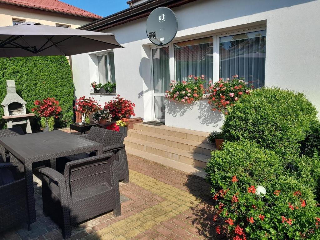 a patio with a table and an umbrella and flowers at Ferienhaus in Kolberg mit Grill und Garten in Kołobrzeg