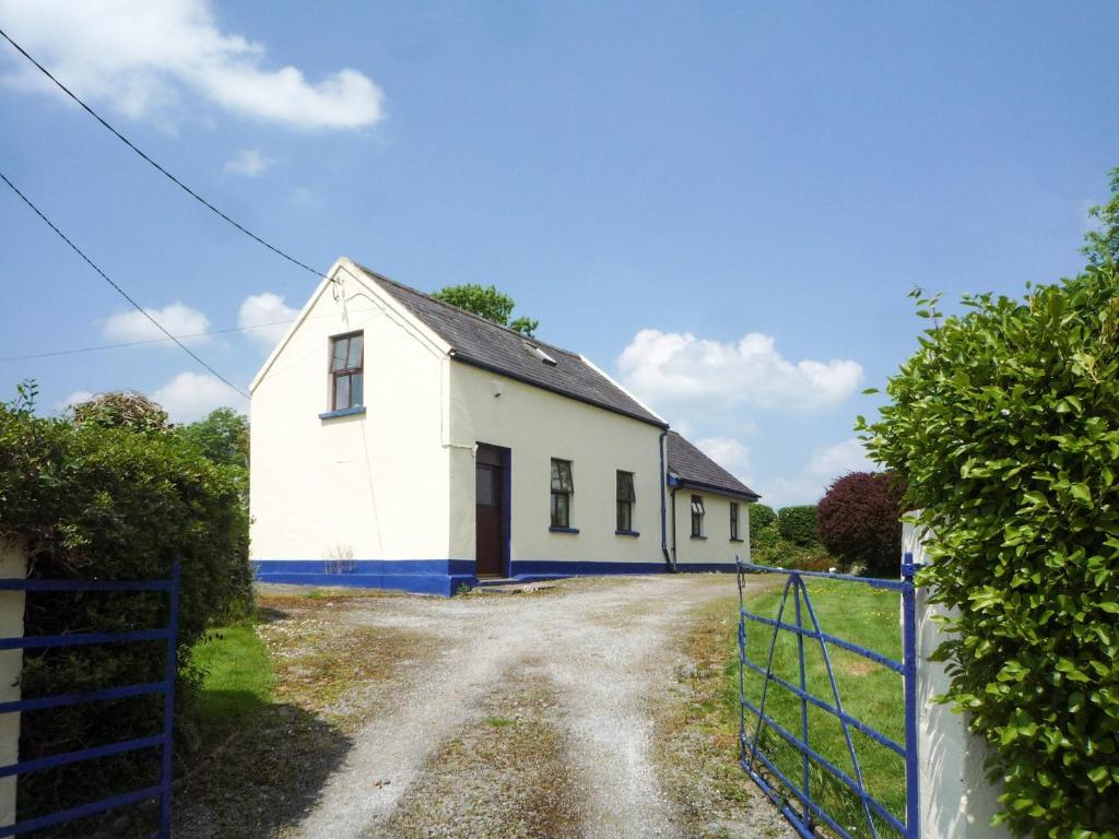 een oud wit huis met een blauw hek bij Sheans Holiday Cottage Killarney by Trident Holiday Homes in Killarney