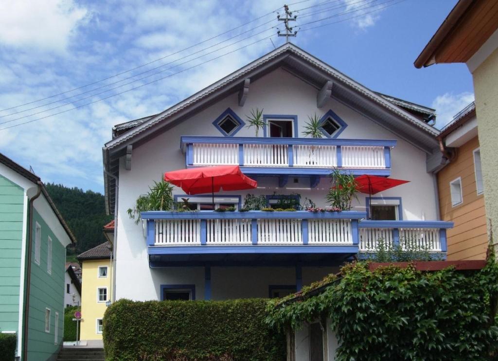 Obernzell的住宿－Ferienwohnung für 2 Personen ca 60 qm in Obernzell, Bayern Bayerischer Wald，一个带红色遮阳伞阳台的房子