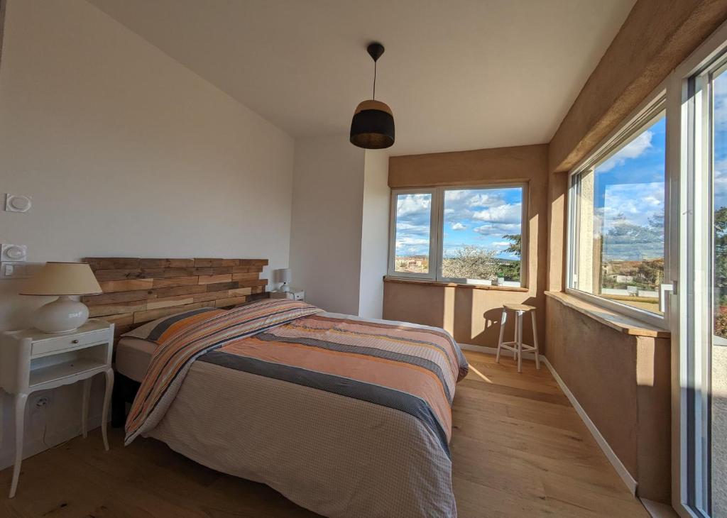 a bedroom with a bed and two windows at Terre de Sienne in Saint-Clair