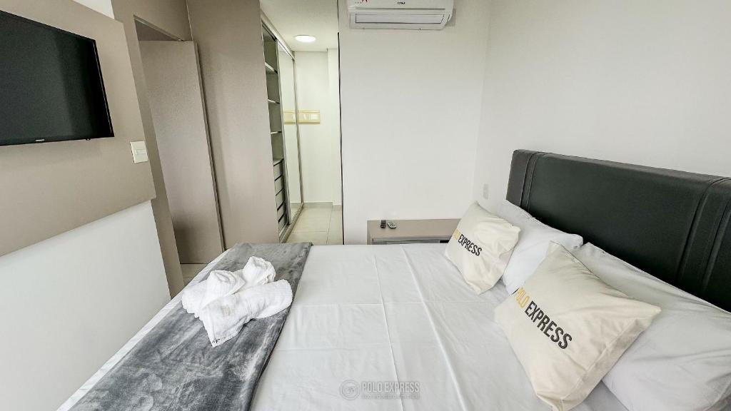 een slaapkamer met een bed met witte lakens en kussens bij Res. Trend Office Apto 2106 Pav. G in Goiânia