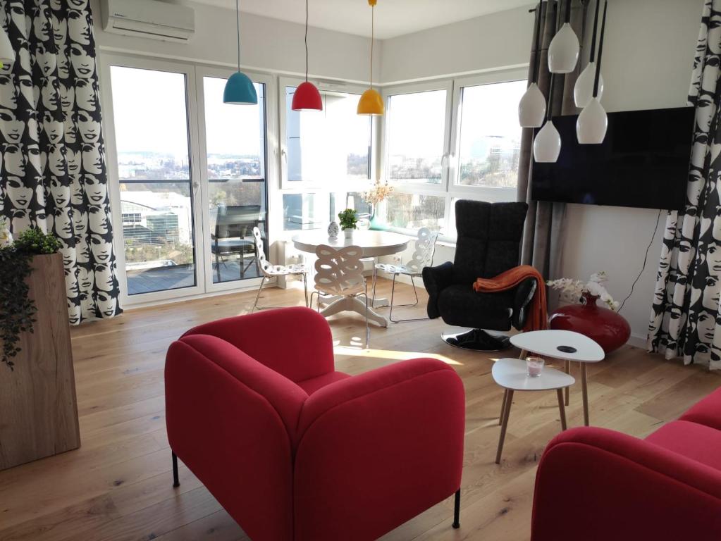 a living room with red chairs and a table at Sloneczny Apartament na 14 Kondygnacji z widiokiem na Bydgoszcz in Bydgoszcz