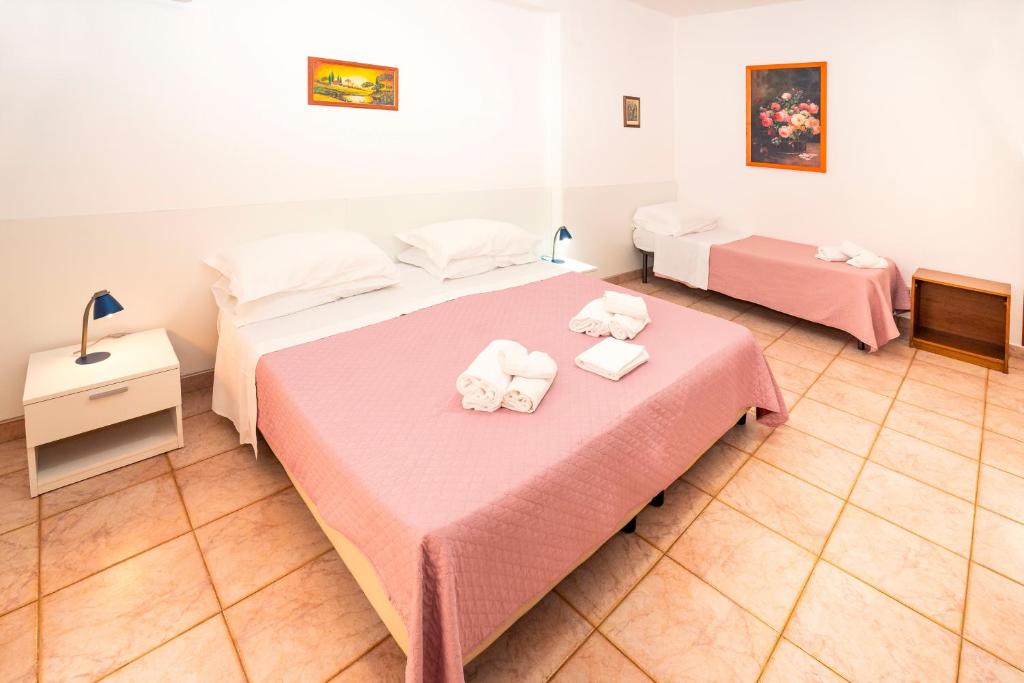 a bedroom with two beds with pink sheets and towels at Hotel Fernanda in Letojanni