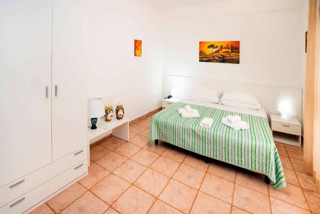 a bedroom with a green and white bed with two towels at Hotel Fernanda in Letojanni